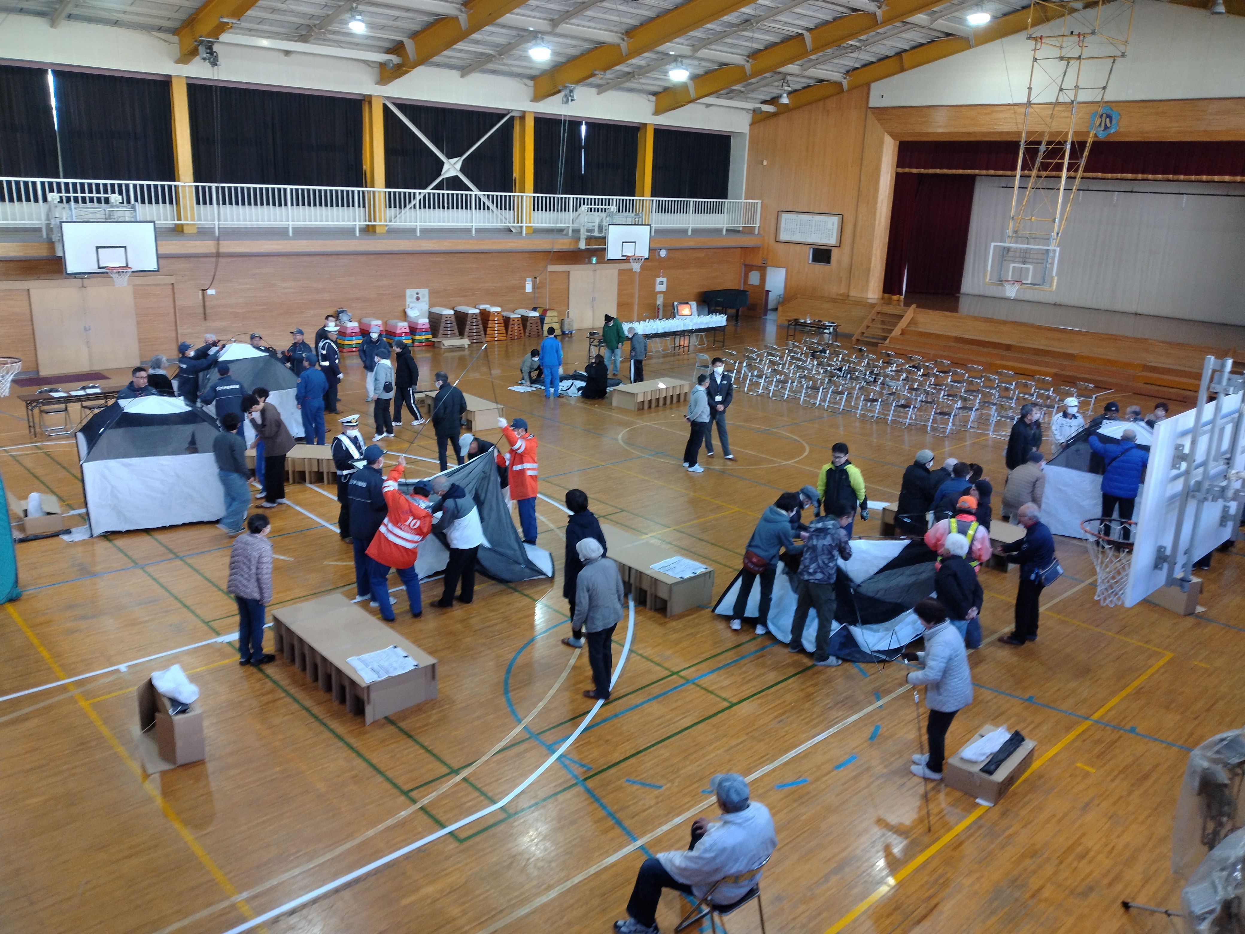 防災室から体育館へ備品を協力して運ぶ参加者たちの様子